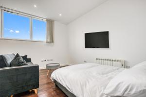 a white bedroom with a bed and a tv at Stylish Studio by Heathrow Airport in London