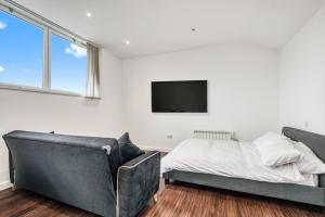 a bedroom with a couch and a tv on the wall at Stylish Studio by Heathrow Airport in London