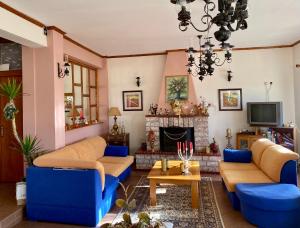 a living room with blue couches and a fireplace at Eleni's Guesthouse in Pisoderi