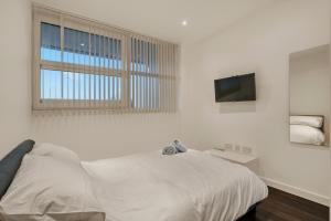 um quarto branco com uma cama e uma televisão em Modern 1 Bed by Heathrow Airport em Londres