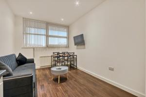 a living room with a couch and a tv at Modern 1 Bed by Heathrow Airport in London