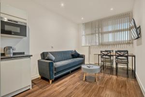 uma sala de estar com um sofá azul e uma mesa em Modern 1 Bed by Heathrow Airport em Londres