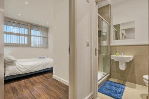 a bathroom with a toilet and a sink and a bed at Modern 1 Bed by Heathrow Airport in London
