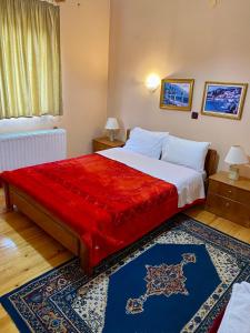 a bedroom with a large bed with a red blanket at Eleni's Guesthouse in Pisoderi