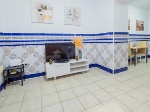 sala de estar con TV y azulejos azules y blancos. en Cubo's Dreams Alhaurin Room 2, en Alhaurín el Grande