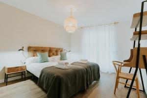 a white bedroom with a bed with towels on it at Natural Stay Apartamentos in Logroño