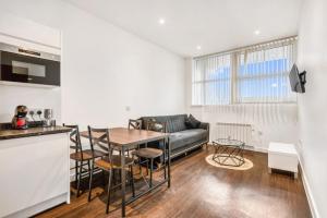 a kitchen and living room with a table and a couch at Fantastic 1 Bed by Heathrow Airport in London