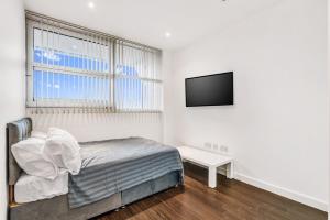 a bedroom with a bed and a flat screen tv at Fantastic 1 Bed by Heathrow Airport in London