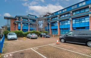 a parking lot with cars parked in front of a building at Fantastic 1 Bed by Heathrow Airport in London