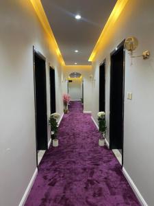 a corridor with a purple carpeted hallway with potted plants at دايموند Diamond in Al-ʿUla
