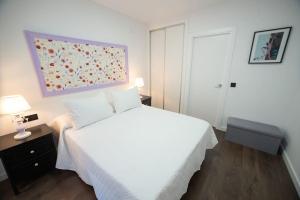 Un dormitorio con una cama blanca y una pintura en la pared en las DOS CATEDRALES 2 en Plasencia