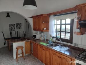 uma cozinha com armários de madeira, um lavatório e uma janela em La Estancia en La Frontera El Hierro em Jerez de la Frontera