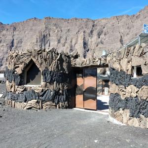 ein Steingebäude mit einem Berg im Hintergrund in der Unterkunft Pensão Repouso Alegre Turismo e Aventura in Portela