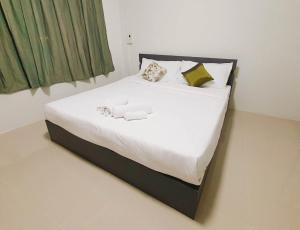 Phakdee Place في تشانتابوري: سرير بشرشف ووسائد بيضاء في الغرفة