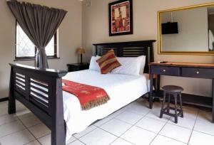 a bedroom with a bed and a desk and a mirror at Ocean View Villas in Ballito