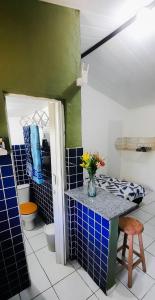 un baño con azulejos azules y un jarrón de flores en un mostrador en Eco chalés 1 e 2 en Cabo de Santo Agostinho