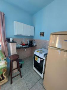 una cucina con frigorifero, piano cottura e sgabello di Casa em Cabo Frio a Cabo Frio