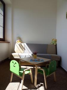 a living room with a table and two green chairs at Penzion Šumavous in Vimperk