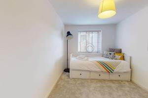 Un dormitorio con una cama blanca y una lámpara. en Magnolia House, en Leamington Spa
