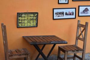 a wooden table and two chairs next to a wall with pictures at La Enramada in Amaichá del Valle