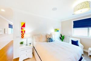 a white bedroom with a large bed and a window at Sunshine Beach Escape in Seal Beach