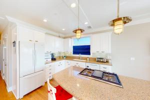 a kitchen with white cabinets and a white refrigerator at Sunshine Beach Escape in Seal Beach