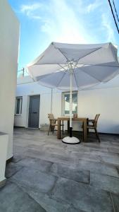 un grande ombrello bianco seduto in cima a un patio di Alexandra's Boutique House a Triovasálos