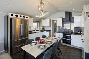 a kitchen with a table with chairs and a refrigerator at Machrihanish Holiday Park in Campbeltown