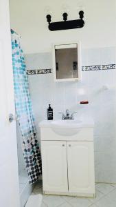 La salle de bains blanche est pourvue d'un lavabo et d'un miroir. dans l'établissement SugaLove Villa 30 Flamboyant Ave, à Saint James