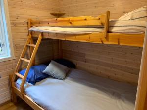 two bunk beds in a wooden room with a ladder at Lofotparadis - nydelig hytte på unikt sted in Valberg