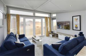 a living room with blue couches and a large window at Machrihanish Holiday Park in Campbeltown