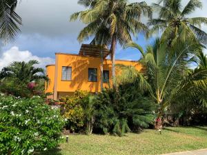 a yellow house with palm trees in front of it at Lions Home in Diani Beach
