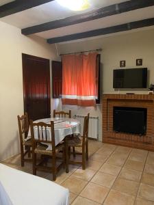 ein Esszimmer mit einem Tisch, Stühlen und einem TV in der Unterkunft Apartamentos de Astroturismo la Cañada in Torrejón el Rubio