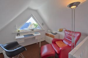 Cette chambre mansardée comprend une chaise rouge et un bureau. dans l'établissement "Schwedenhaus" Das Schwedenhaus, Whg Karlsson, à Büsum