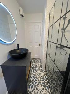 baño con lavabo negro y espejo en Two bedroom townhouse in the heart of Dungarvan en Dungarvan