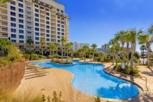 uma piscina de resort com palmeiras e um edifício em Luau #6633 em Destin