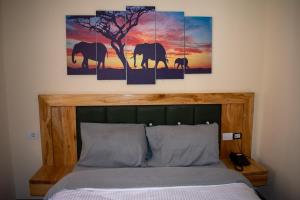 a bedroom with a bed with two paintings of elephants at Choice Guest House 2 in Addis Ababa