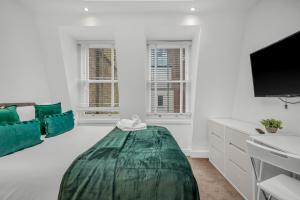 a white living room with a couch and a tv at Two Bedroom Serviced Apartment in Artillery Lane in London