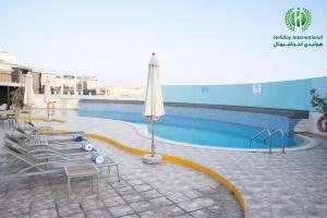 Holiday International Hotel Embassy District في دبي: مسبح بكراسي ومظلة