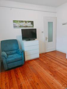 un salon avec une chaise bleue et une télévision dans l'établissement Al borgo di Sant'Orso - CIR 0342, à Aoste