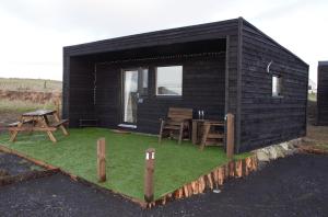 a small black cabin with a table and a bench at The Windy Roost in Occumster