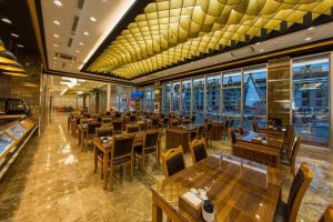 un restaurant avec des tables et des chaises en bois ainsi que des fenêtres dans l'établissement GHERDAN GOLD OTEL, à Konya