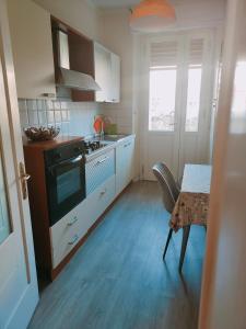 - une cuisine avec des placards blancs, une table et une cuisinière dans l'établissement Al borgo di Sant'Orso - CIR 0342, à Aoste
