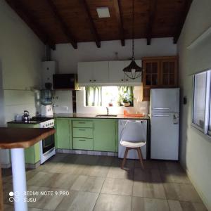 cocina con armarios verdes y nevera blanca en Casa El Alto en Villa General Belgrano