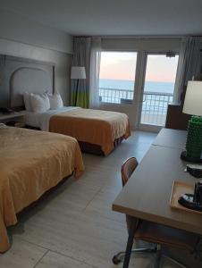 Quality Inn & Suites Oceanfront في فرجينيا بيتش: غرفة فندقية بسريرين وبلكونة