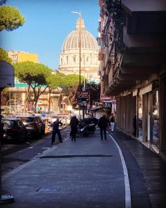 een groep mensen die door een straat lopen met een gebouw bij A Casa di Zia Vaticano in Rome