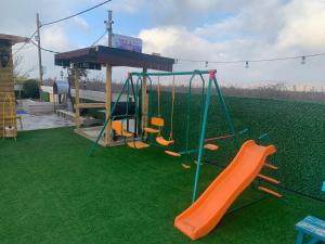 um parque infantil com um escorrega laranja na relva em מפגש הדובדבן em Buq‘ātā