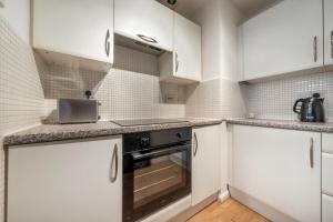 a kitchen with white cabinets and a black oven at Luxury 2 Bed Apartment Stansted Airport Bishops Stortford in Bishops Stortford