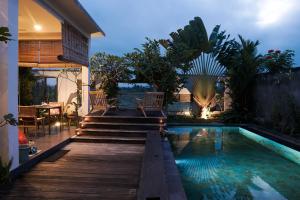 een achtertuin met een zwembad en een houten terras bij Ikan Villa Ubud in Ubud