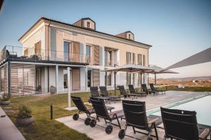 Villa con piscina y patio con sillas. en Villa Vinory Bricco di Nizza, en Nizza Monferrato